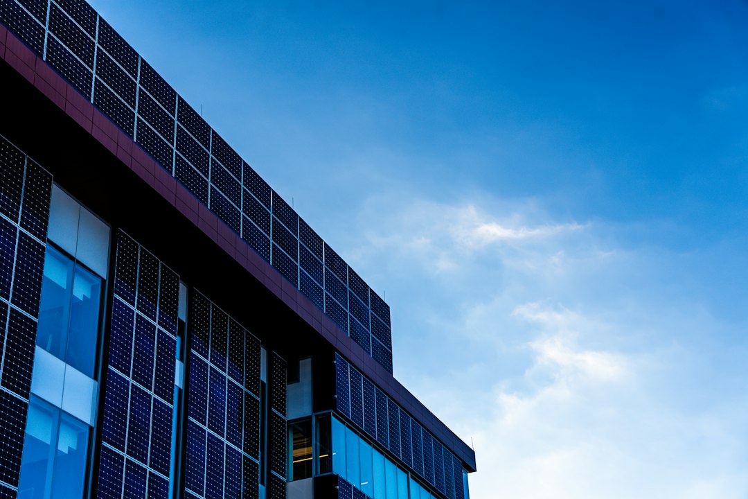 Paneles Solares Bifaciales: Cuándo Merecen la Pena en Cubiertas y Suelos: Modern building facade with solar panels against blue sky