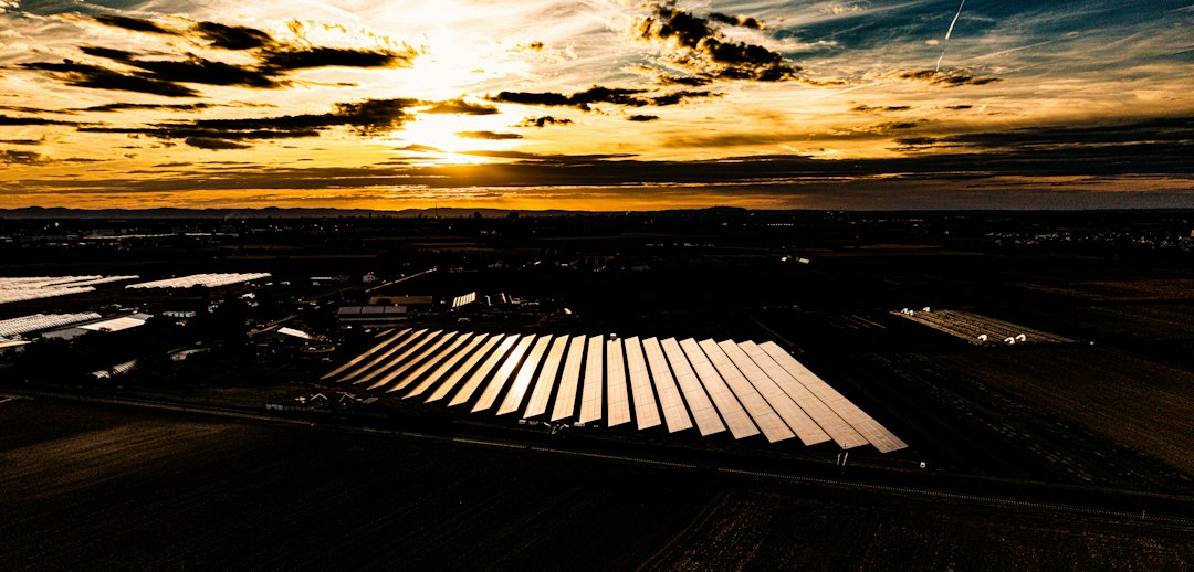 Cómo Funcionan los Diodos de Bypass Frente a las Sombras en Paneles Solares: Aerial view of a solar farm reflecting low sun in a rural landscape