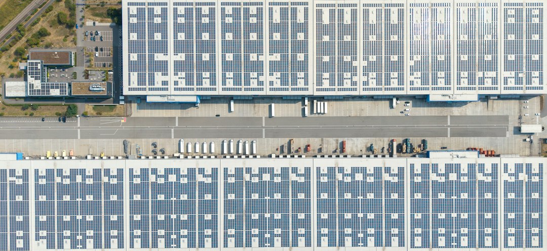 Monitorización de Curvas de Carga Horarias: Dónde se Escapa la Energía Solar: An aerial view of large warehouse roofs covered in solar panels with loading doc